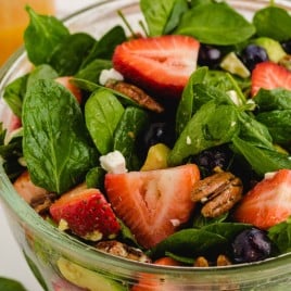 A bowl of fruit and vegetable salad, with Spinach and Strawberry