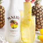 A group of glass bottles on a table, with Malibu and Pineapple