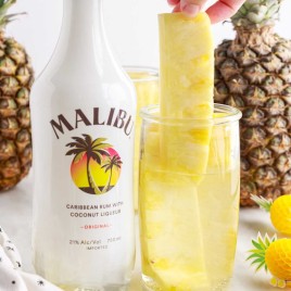 A group of glass bottles on a table, with Malibu and Pineapple