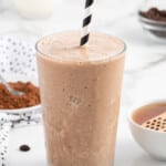 A coffee smoothie in a tall glass with a straw.
