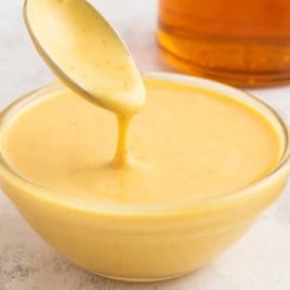 A bowl of soup and a spoon on a table, with Honey and Mustard