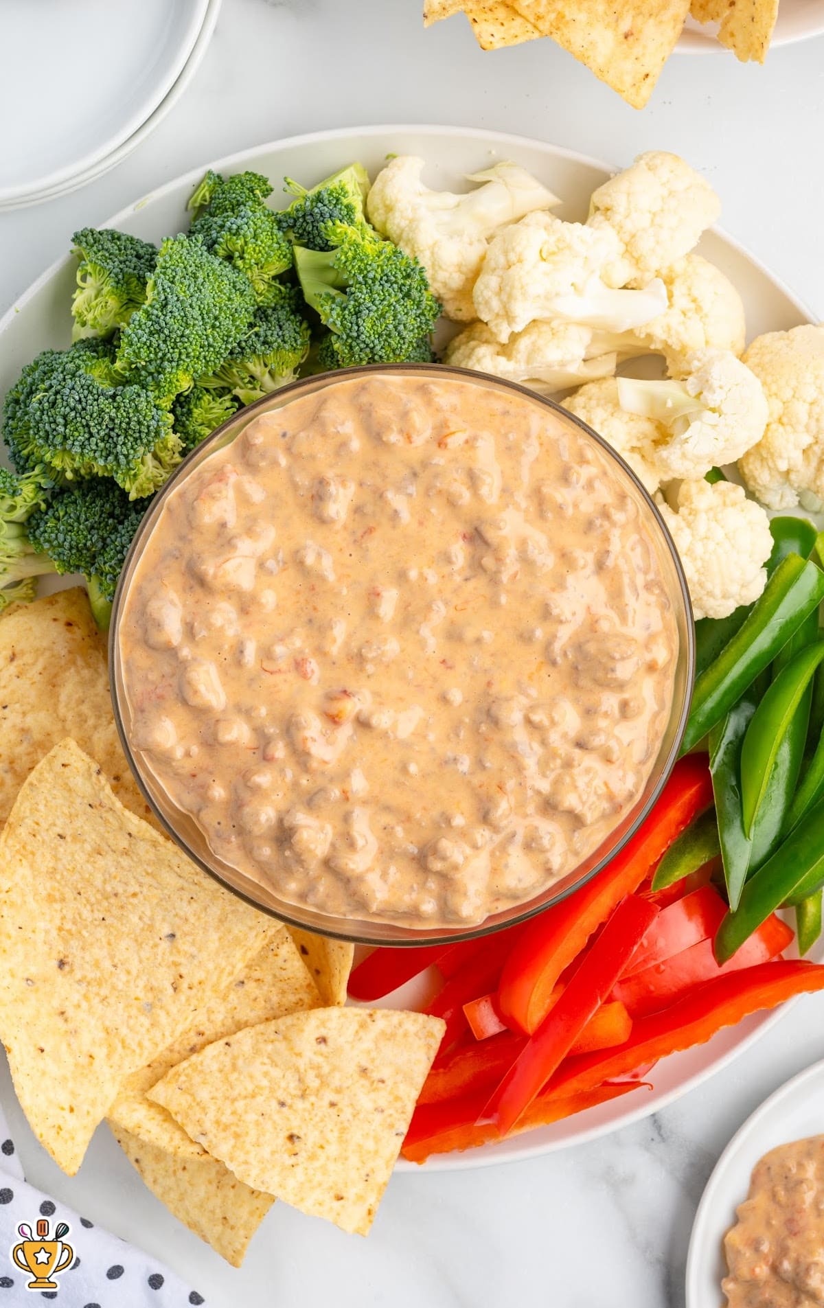 Overhead view of slow cooker Rotel dip showing the creamy, chunky texture with ground beef and Rotel tomatoes, served with chips and fresh veggie dippers.
