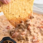 Cheesy Rotel dip being scooped with a tortilla chip, highlighting the melty Velveeta, seasoned beef, and tomatoes in this easy 3-ingredient crockpot appetizer.