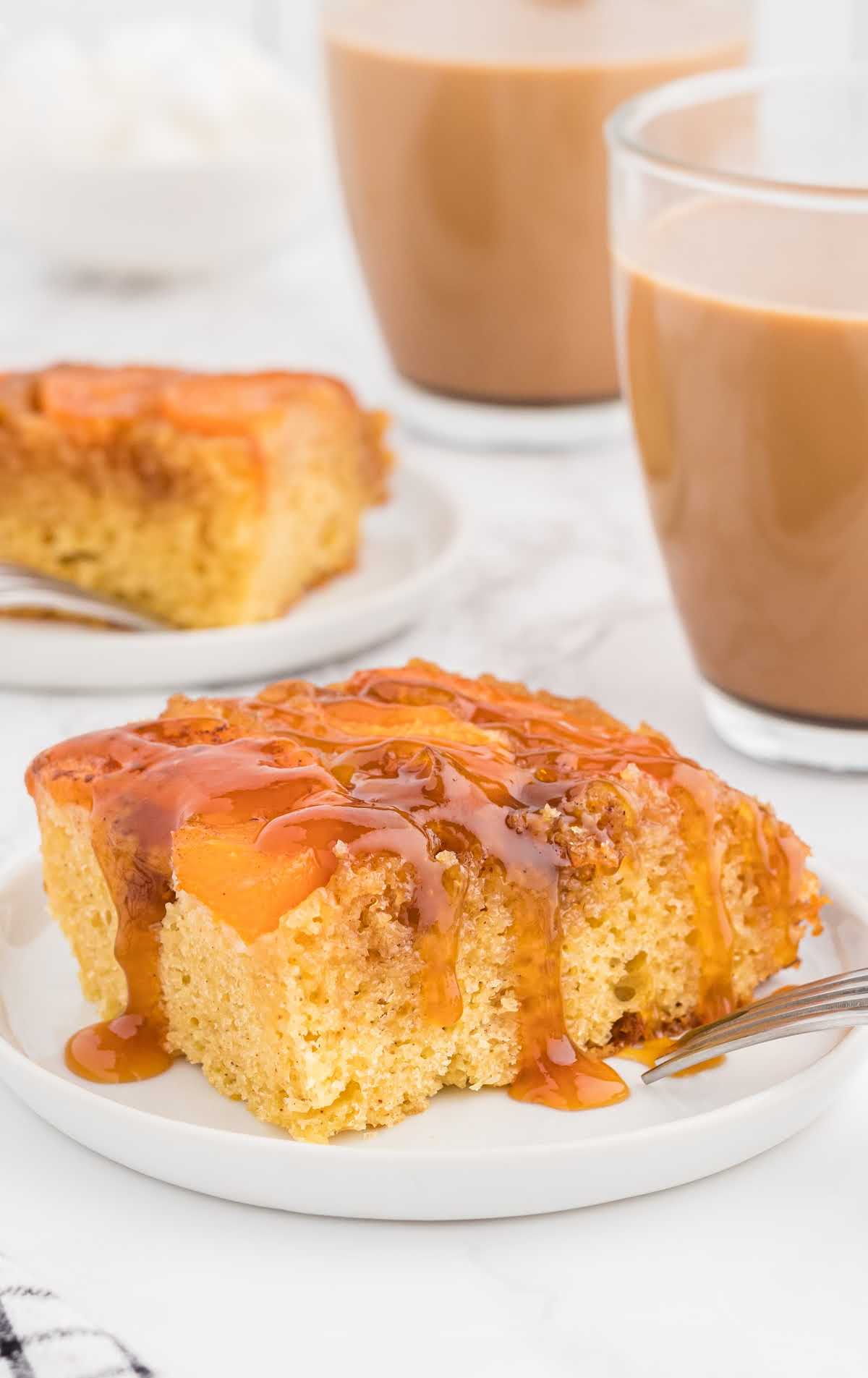 A slice of cake on a plate next to a cup of coffee, with Peach and side