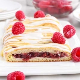 A plate of food with a slice of cake on a table, with Raspberry