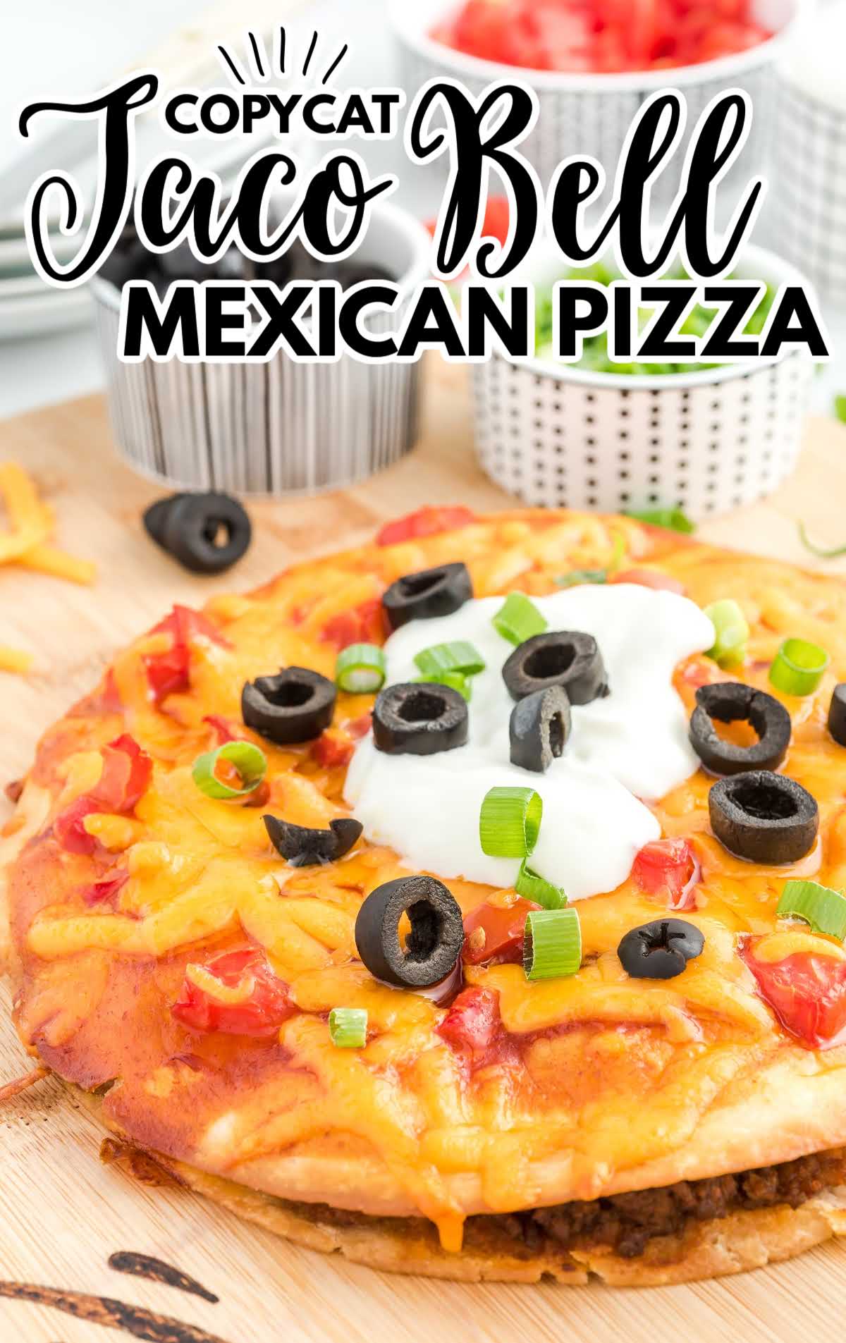 A pizza sitting on top of a cutting board with a cake, with Taco Bell