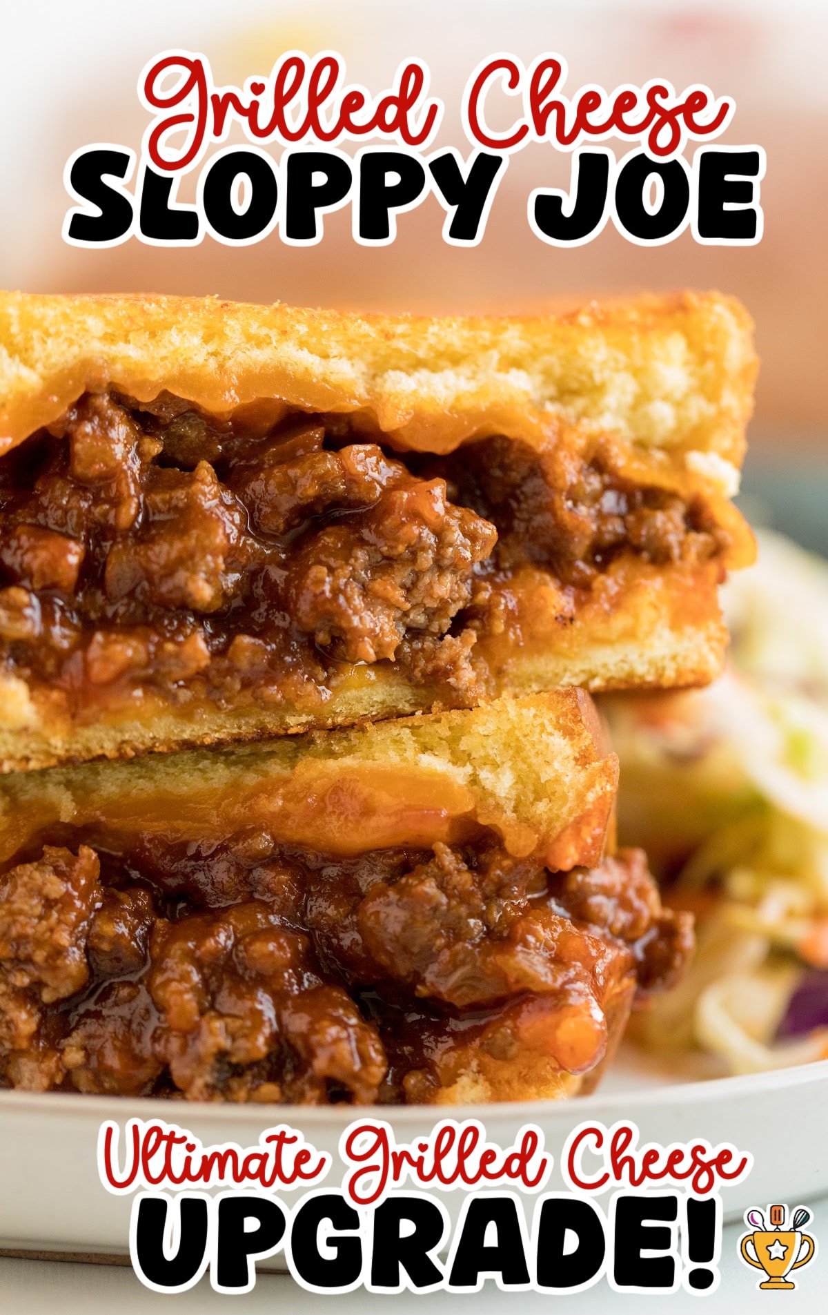 Close-up of a grilled cheese sloppy joe sandwich stacked in halves, showing toasted golden bread filled with melted cheddar cheese and saucy ground beef sloppy joe mixture. The sandwich is gooey and rich with layers of cheese and meat spilling out between the bread. Bold text at the top reads “Grilled Cheese Sloppy Joe” in red and black fonts, while text at the bottom says “Ultimate Grilled Cheese Upgrade!” in red and black with a small gold trophy icon. In the background, a side of coleslaw is slightly blurred.