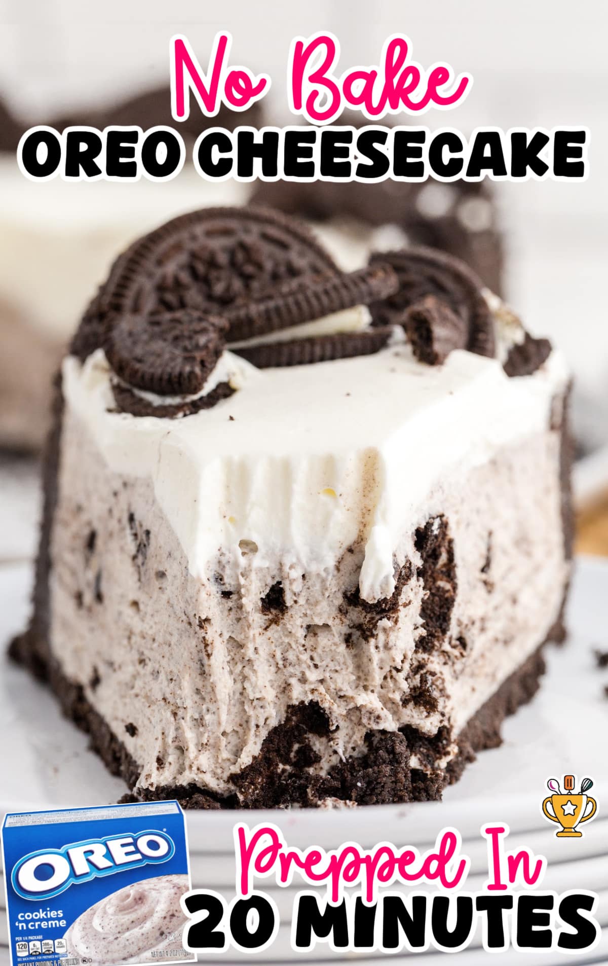 Slice of no bake Oreo cheesecake with a thick Oreo cookie crust, creamy cookies and cream filling, and whipped topping garnished with Oreo pieces. A bite is taken from the slice, showing the smooth texture. Bold text at the top reads &ldquo;No Bake Oreo Cheesecake&rdquo; in pink and black fonts, while text at the bottom says &ldquo;Prepped In 20 Minutes&rdquo; in pink and black with a small gold trophy icon. In the lower left corner, a small image of an Oreo cookies &rsquo;n creme box is included.