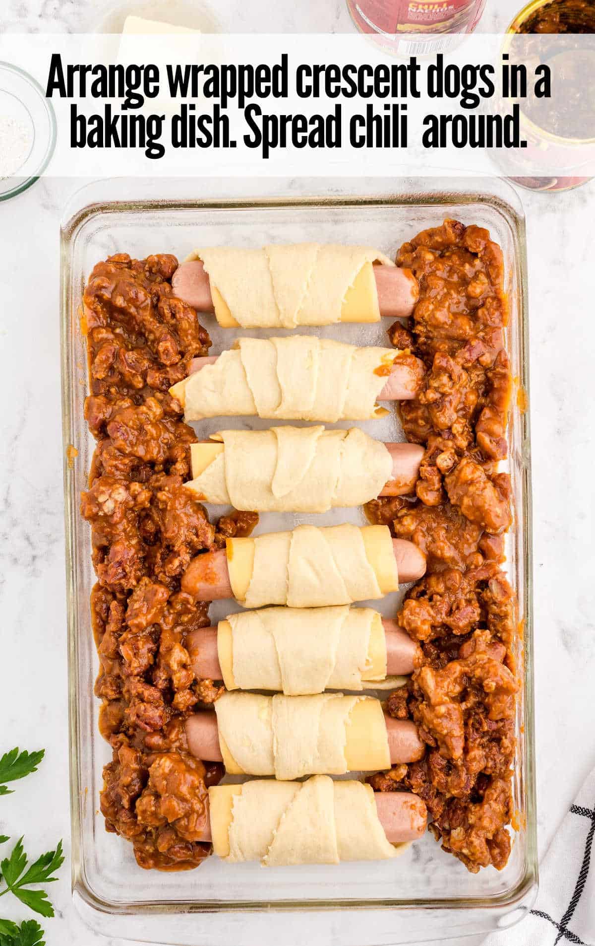 wrapped dogs and chili placed in a baking dish