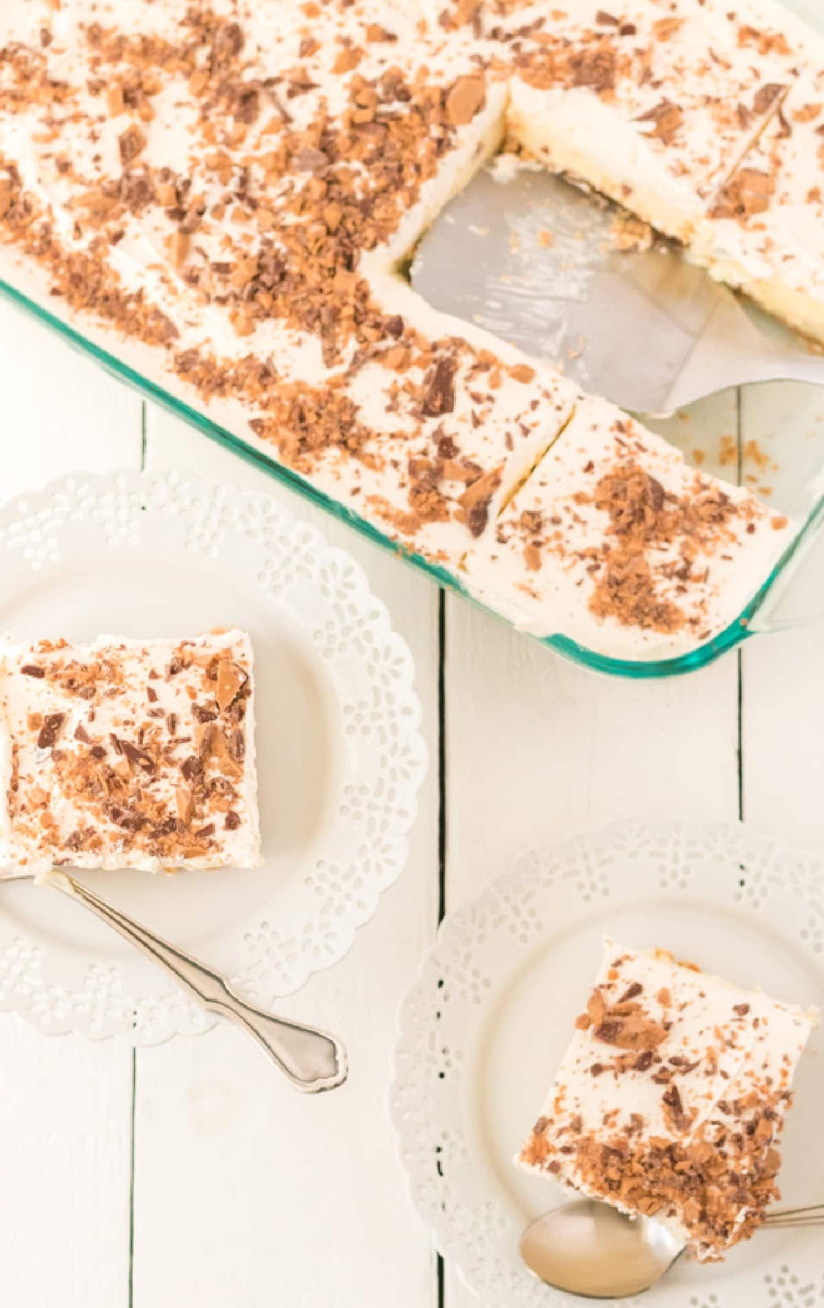 Full pan of no-bake butter pecan crunch with one slice removed, showing fluffy whipped topping and crunchy toffee pecan pieces on top.