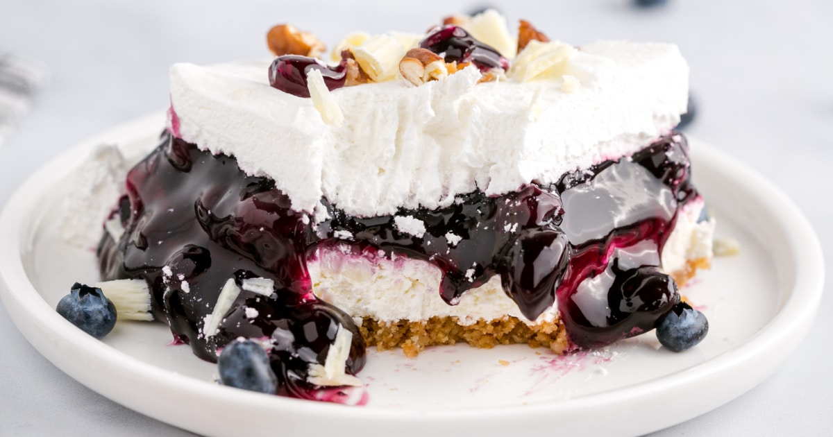 slice of blueberry delight topped with pecans and white chocolate curls on a plate