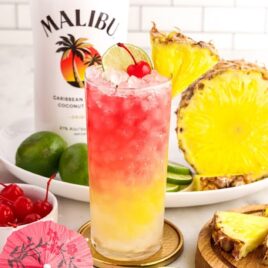 Malibu Cocktail garnished with a cherry, sliced pineapple, and a slice of lime