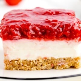 close up shot of a slice of raspberry cheesecake on a plate with a raspberry