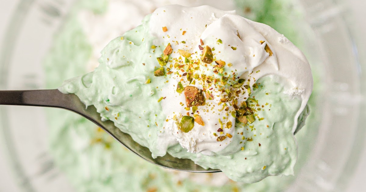 close up shot of a spoonful of pistachio salad topped with whipped cream and crushed pistachios