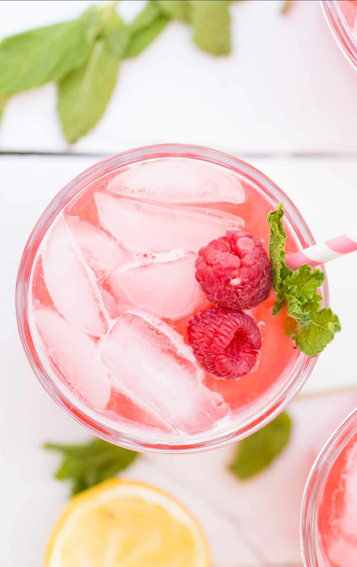 Raspberry Lemonade served in a glass and topped with raspberries and mint