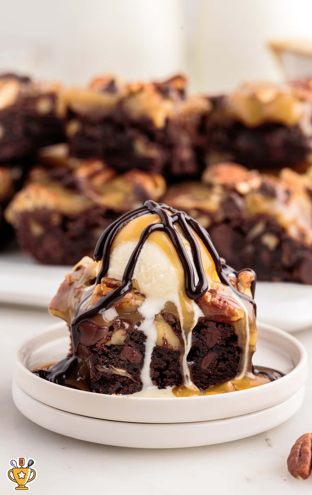close up shot of turtle brownies served on a plate with ice cream, chocolate sauce, and caramel