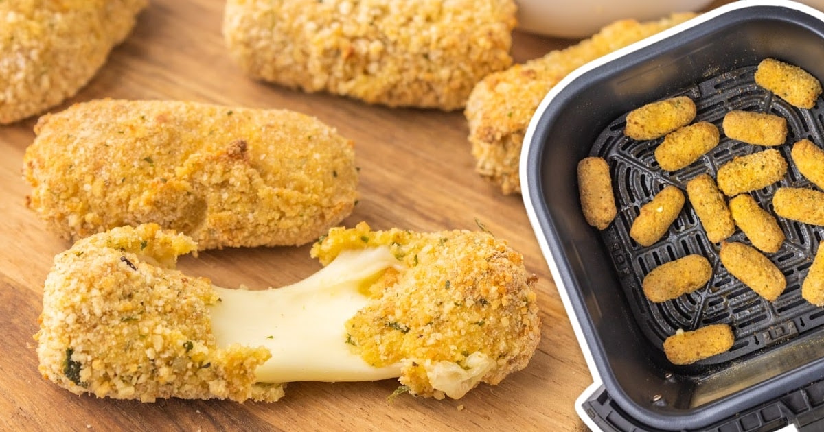 a close up shot of Air Fryer Mozzarella Sticks on a plate with one being pulled apart"