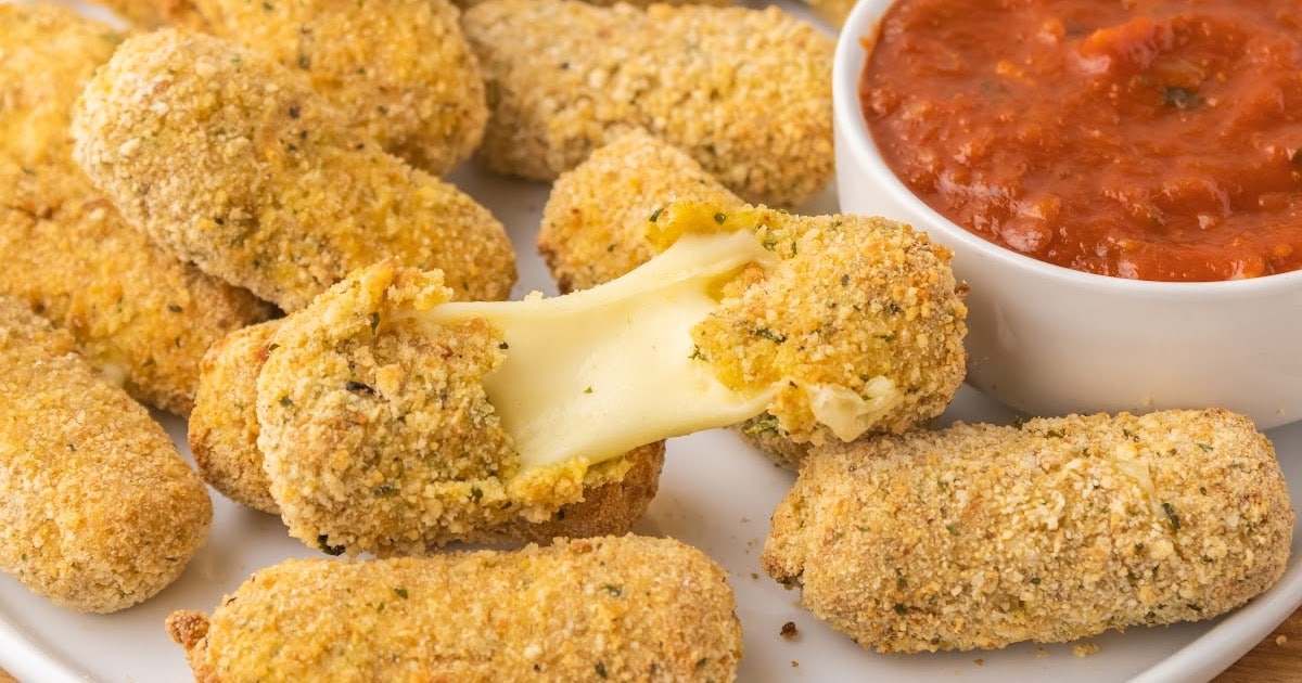 a close up shot of Air Fryer Mozzarella Sticks on a plate with one being pulled apart