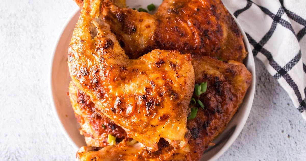 close up shot of Baked Chicken Legs garnished with green onions on a plate