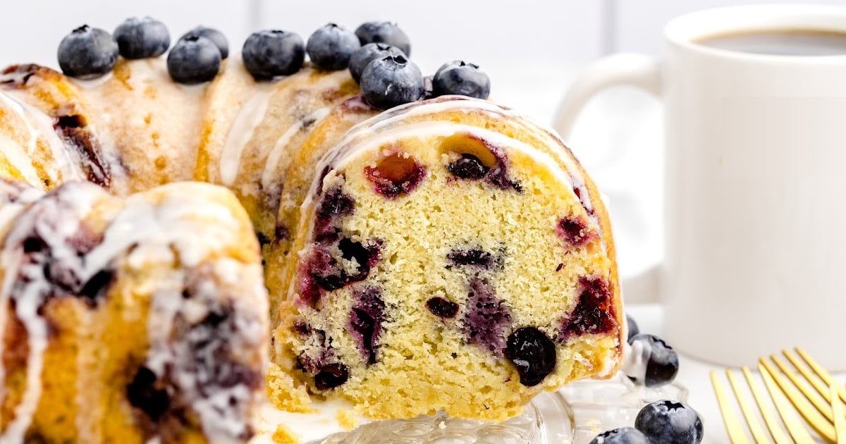 close up shot of a loaf of pound cake topped with glaze and blueberries