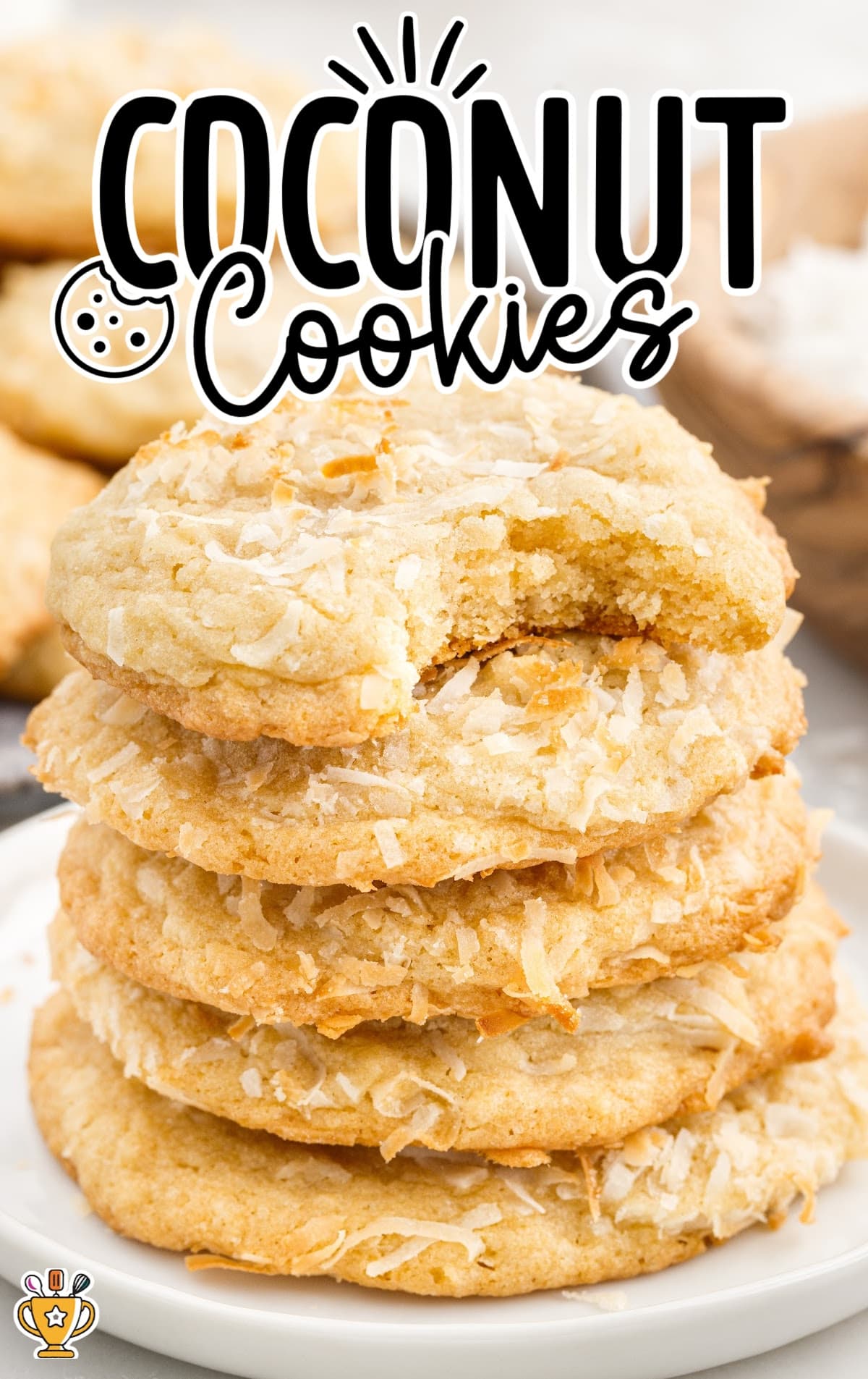 a close up shot of Coconut Cookies stacked on top of each other on a plate with one having a bite taken out of it