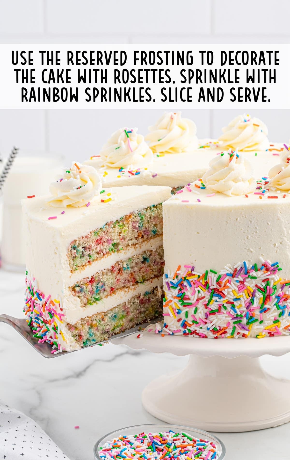 cake topped with frosting and rainbow sprinkles on a cake stand