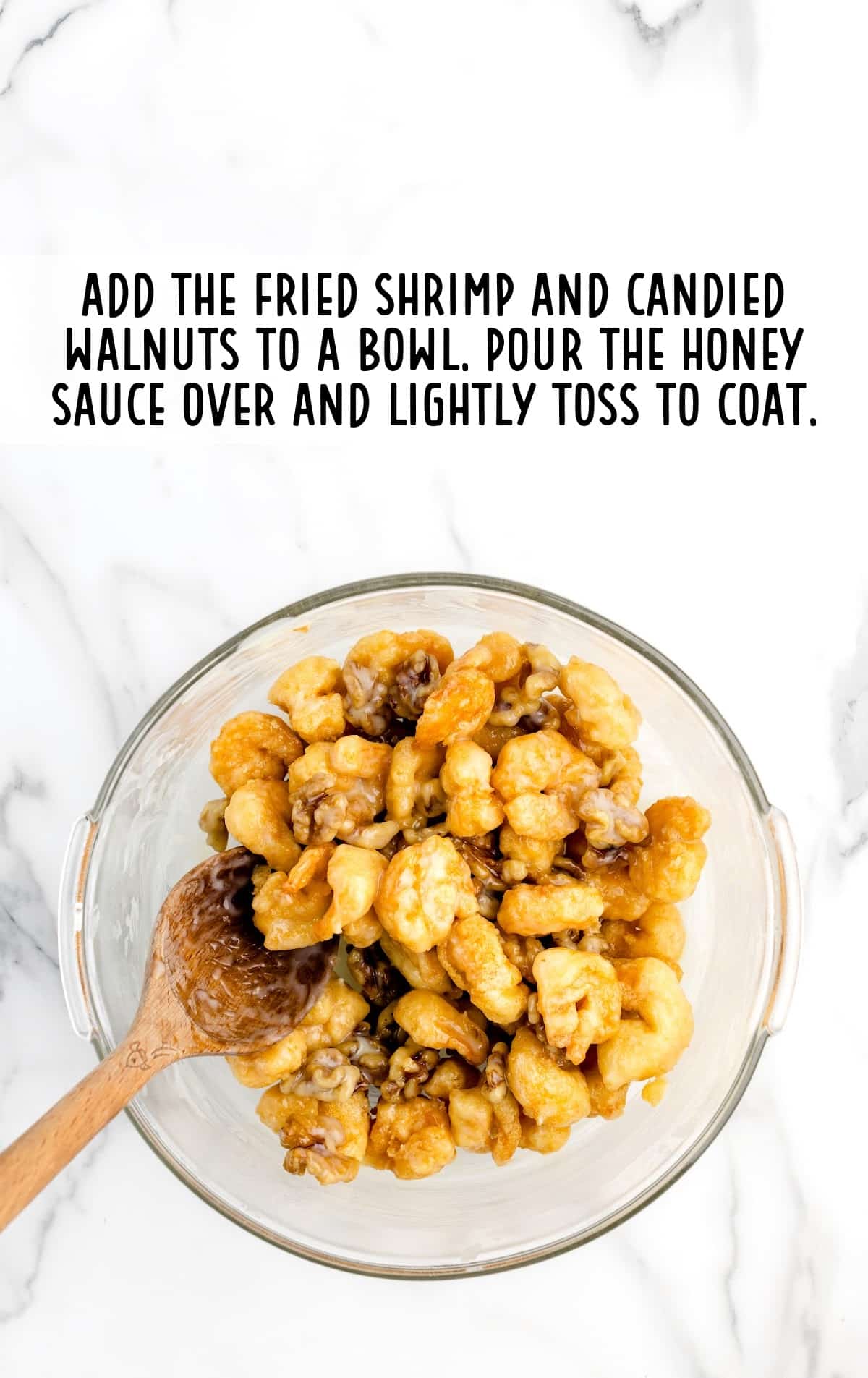 honey sauces poured over the shrimp and walnuts in a bowl
