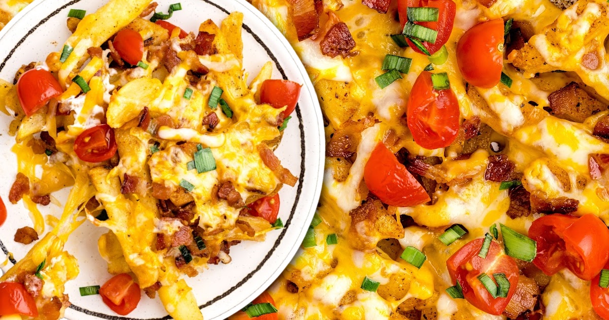 close up overhead shot of a aluminum foil of Dirty Fries topped with cheese then garnished with bacon bits and green onions