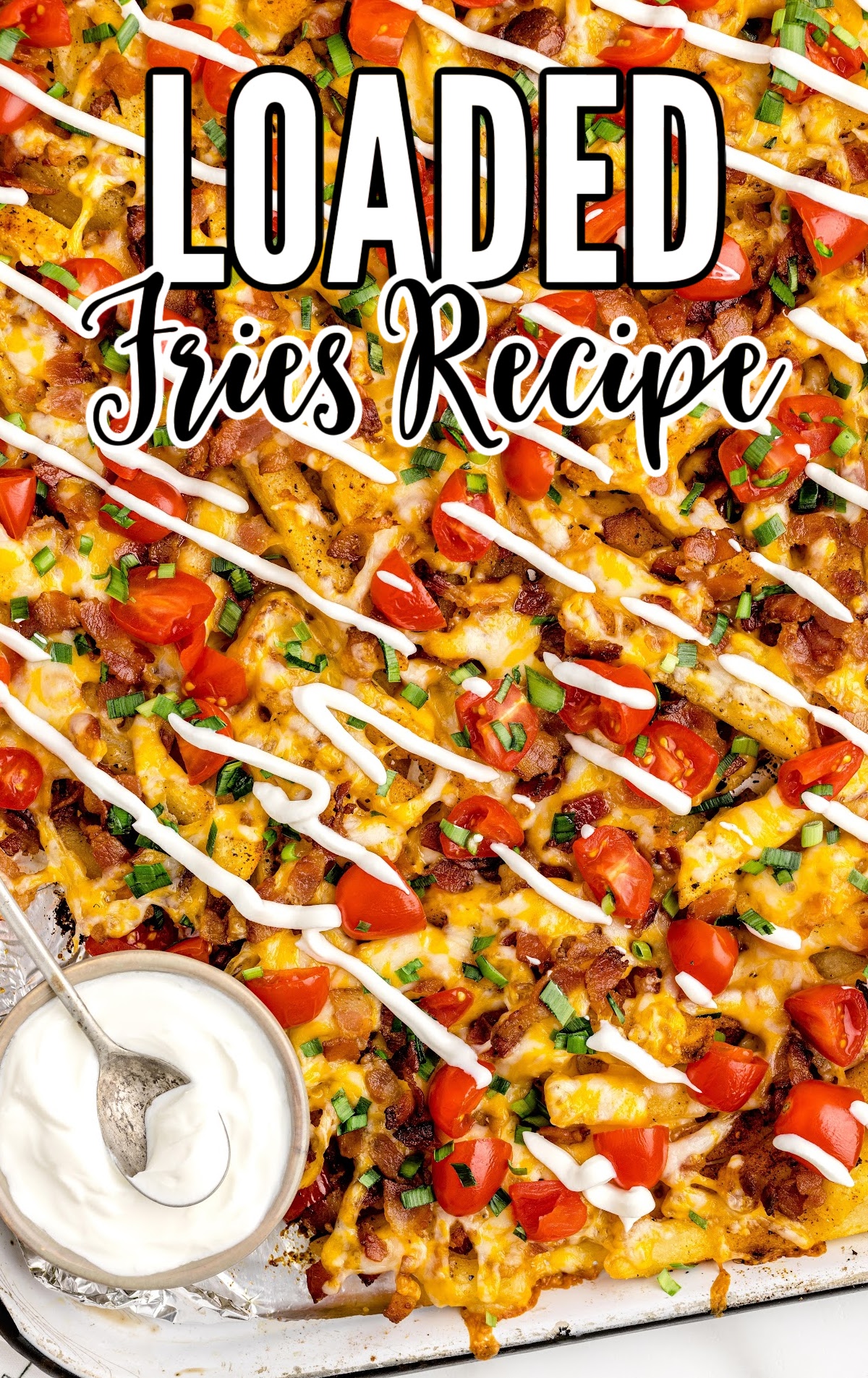 overhead shot of Loaded Fries on a baking tray with a side of sour cream