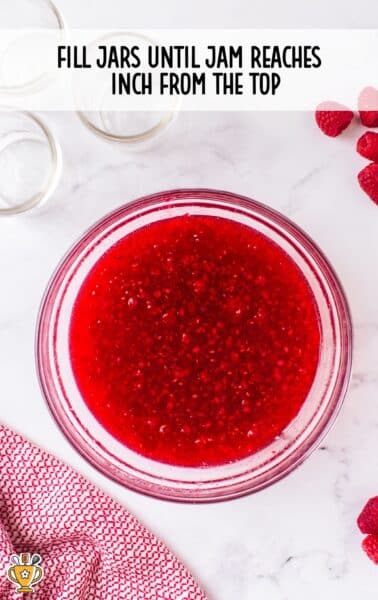raspberry freezer jam being placed into a mason jar