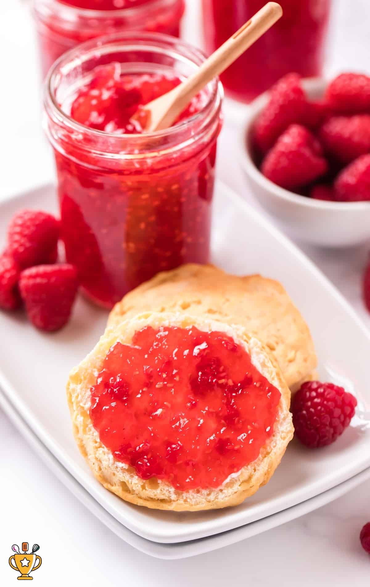 close up shot of a jar of Raspberry Freezer Jam on an english muffin being served