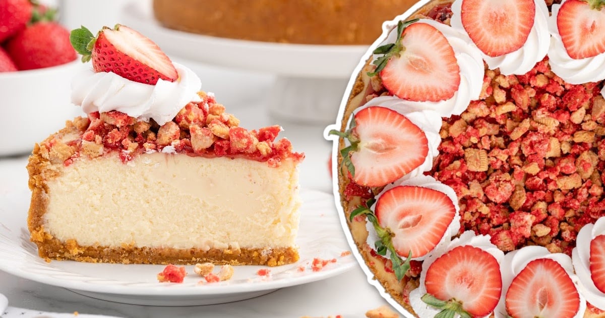 slice of strawberry crunch cheesecake on a plate topped with whipped cream and fresh strawberries