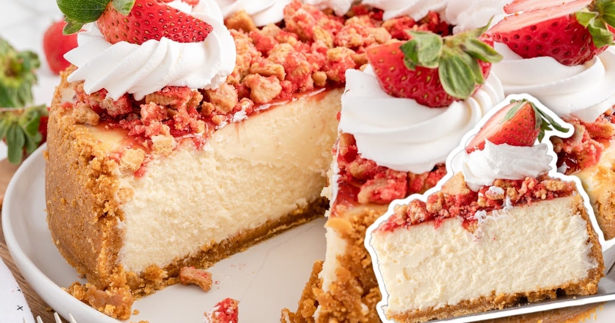 slice of strawberry crunch cheesecake on a plate topped with whipped cream and fresh strawberries