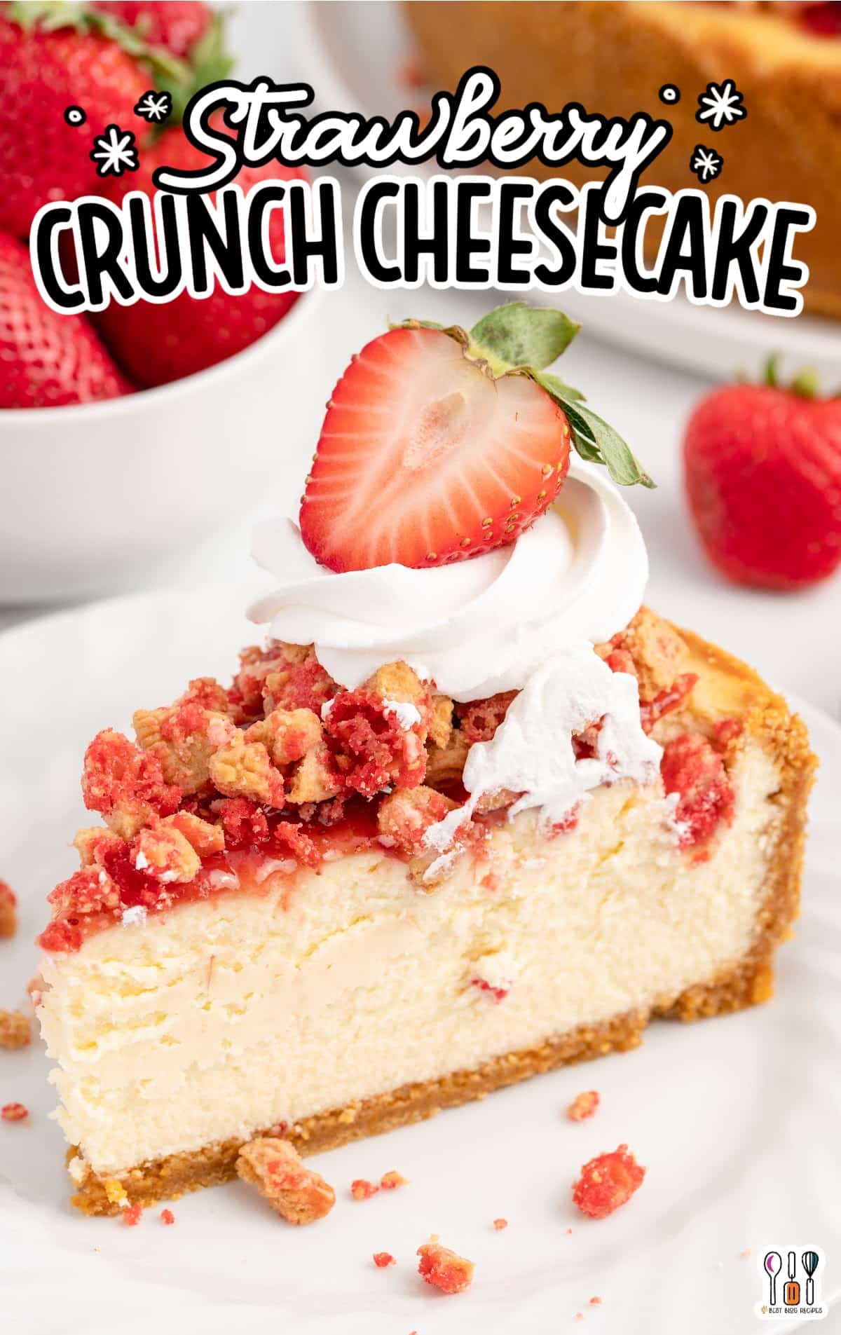 slice of strawberry crunch cheesecake on a plate topped with whipped cream and a fresh sliced strawberry