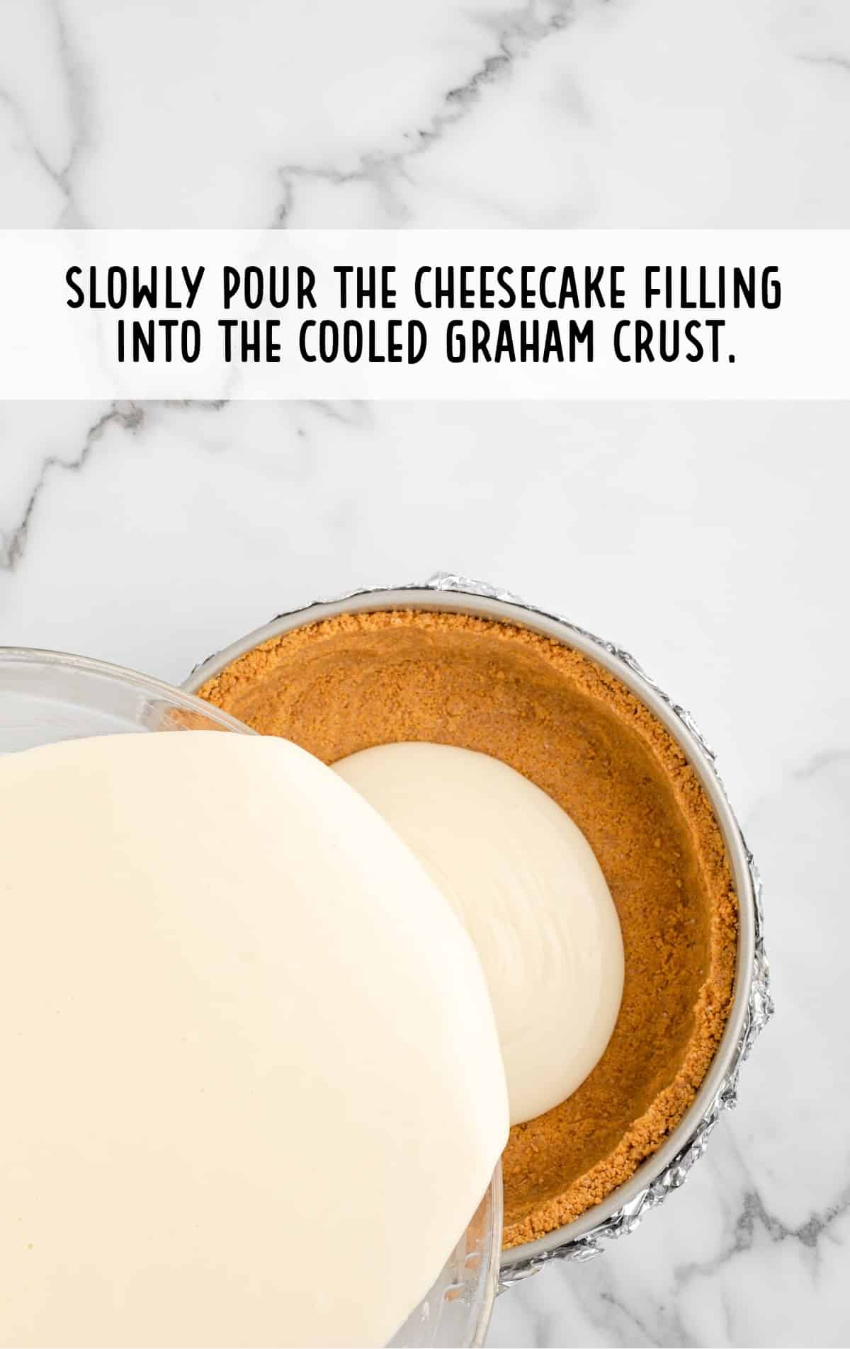 pouring cheesecake batter into a graham cracker crust before baking