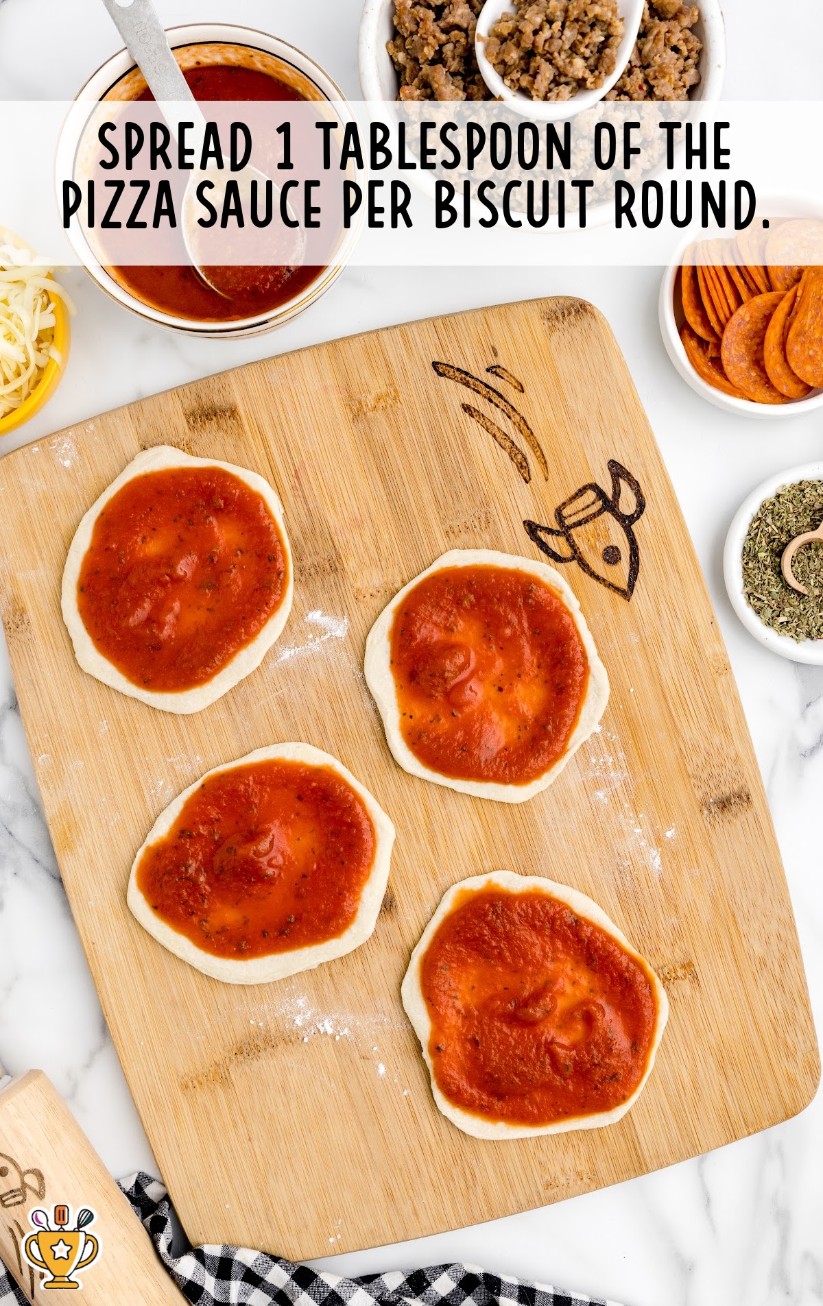 pizza sauce spread on the biscuit round on a wooden board