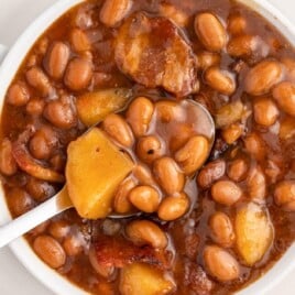 a bowl of Apple Pie Baked Beans with a spoon