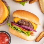 Close up of a baked burger on a bun with toppings.