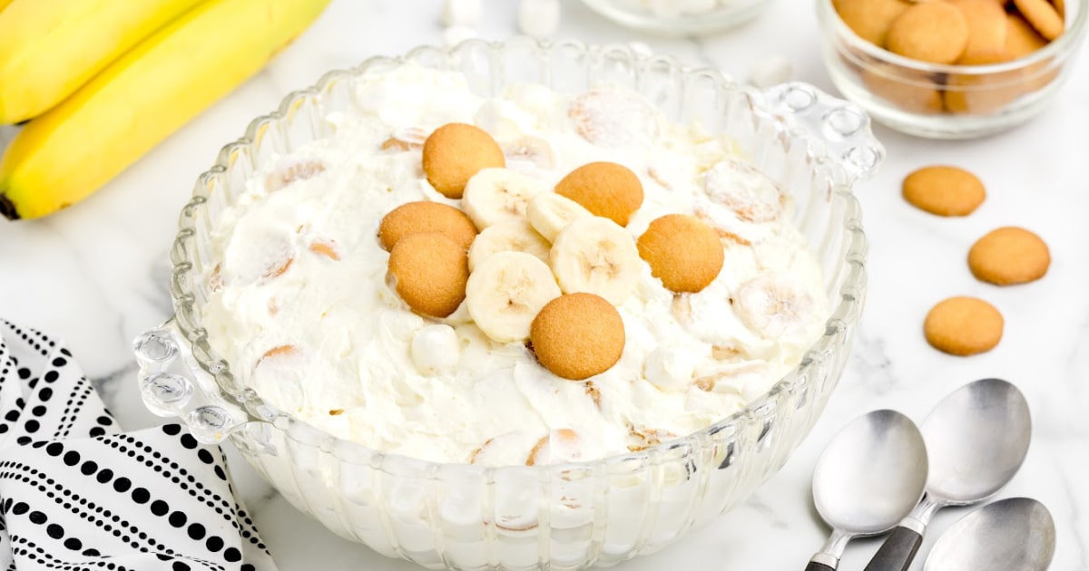 A large serving bowl of banana fluff garnished with banana slices and vanilla wafers.