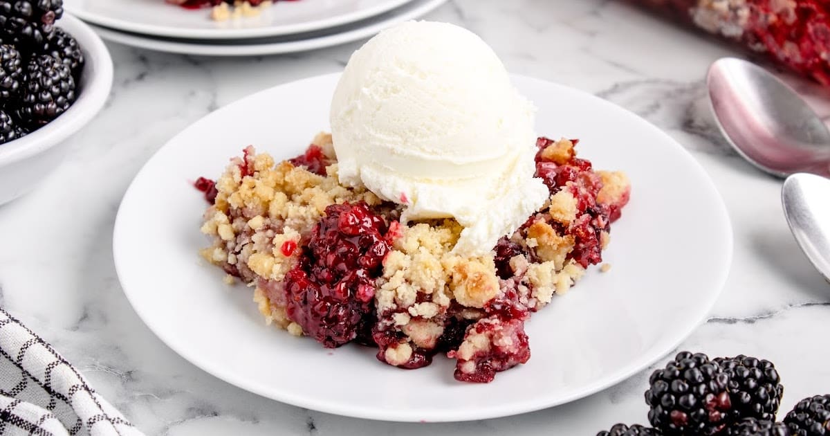 close up shot of a serving of peach dump cake topped with whipped cream