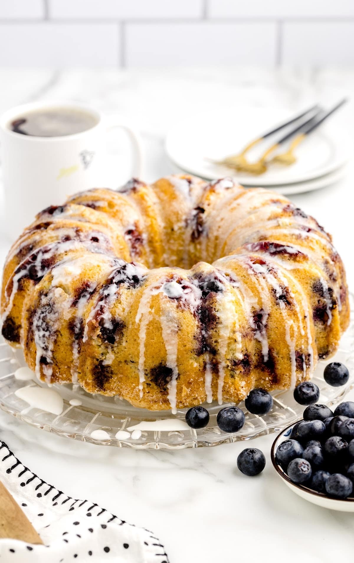 close up shot of a loaf of pound cake topped with glaze and blueberries