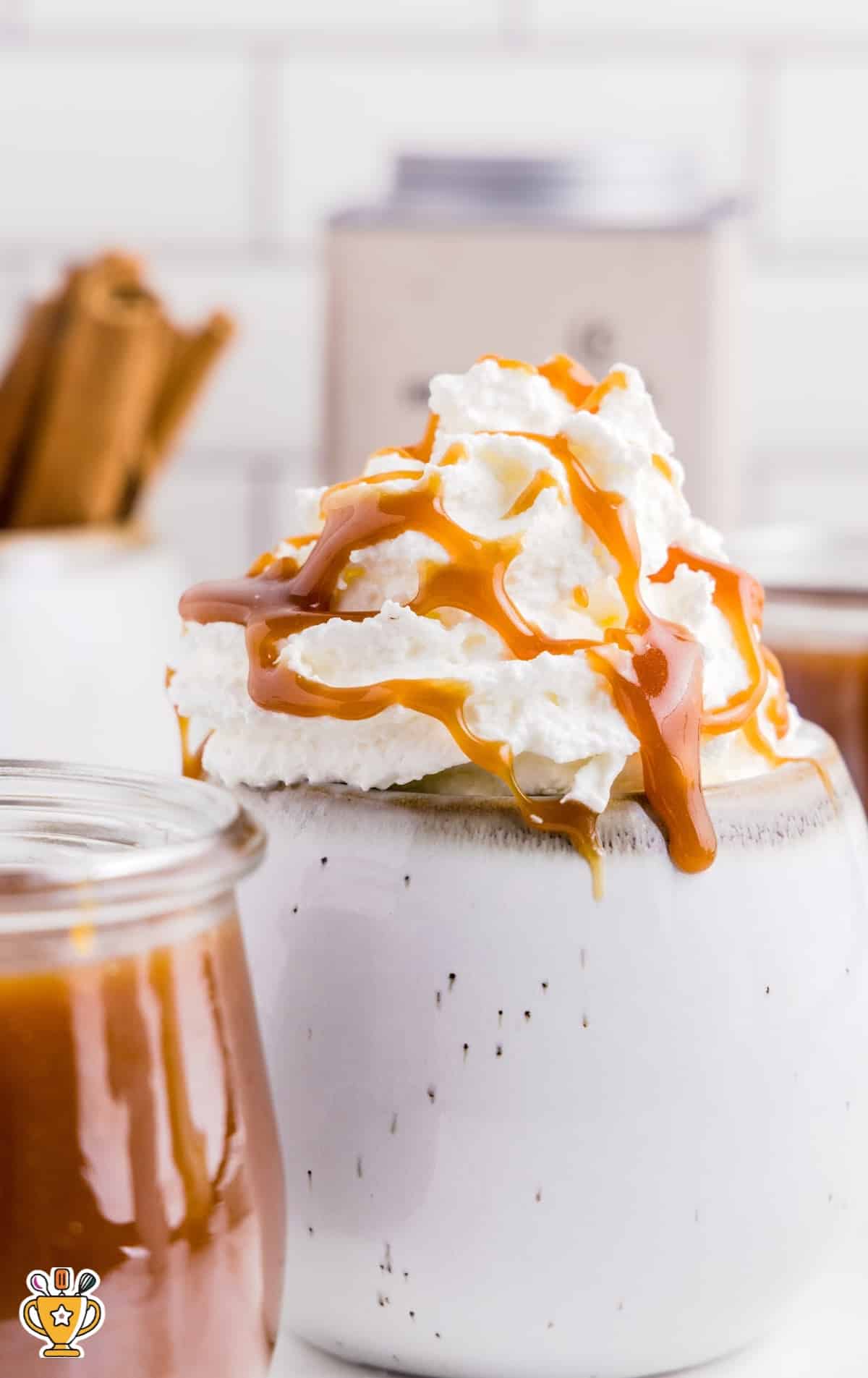 close up shot of Caramel Sauce in a jar with a spoonful of sauce being scooped out of the jar