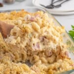 A pan of chicken cordon bleu casserole with a serving spoon lifting a scoop out.