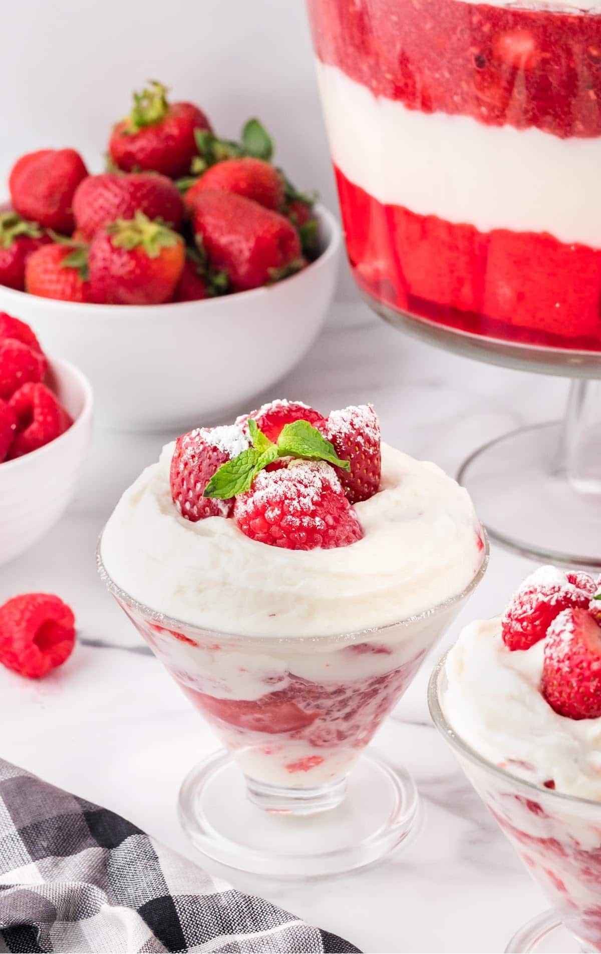 close up shot of a big serving bowl of trifle topped with chopped strawberries