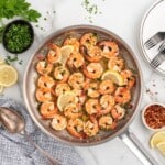lemon garlic shrimp cooked in a pan with lemon wedges