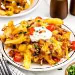 a white plate with a serving of loaded fries