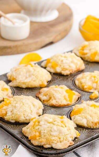 close up shot of peach cobbler muffins in a muffin pan