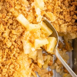 a serving spoon scooping a spoonful of pineapple casserole from the casserole dish