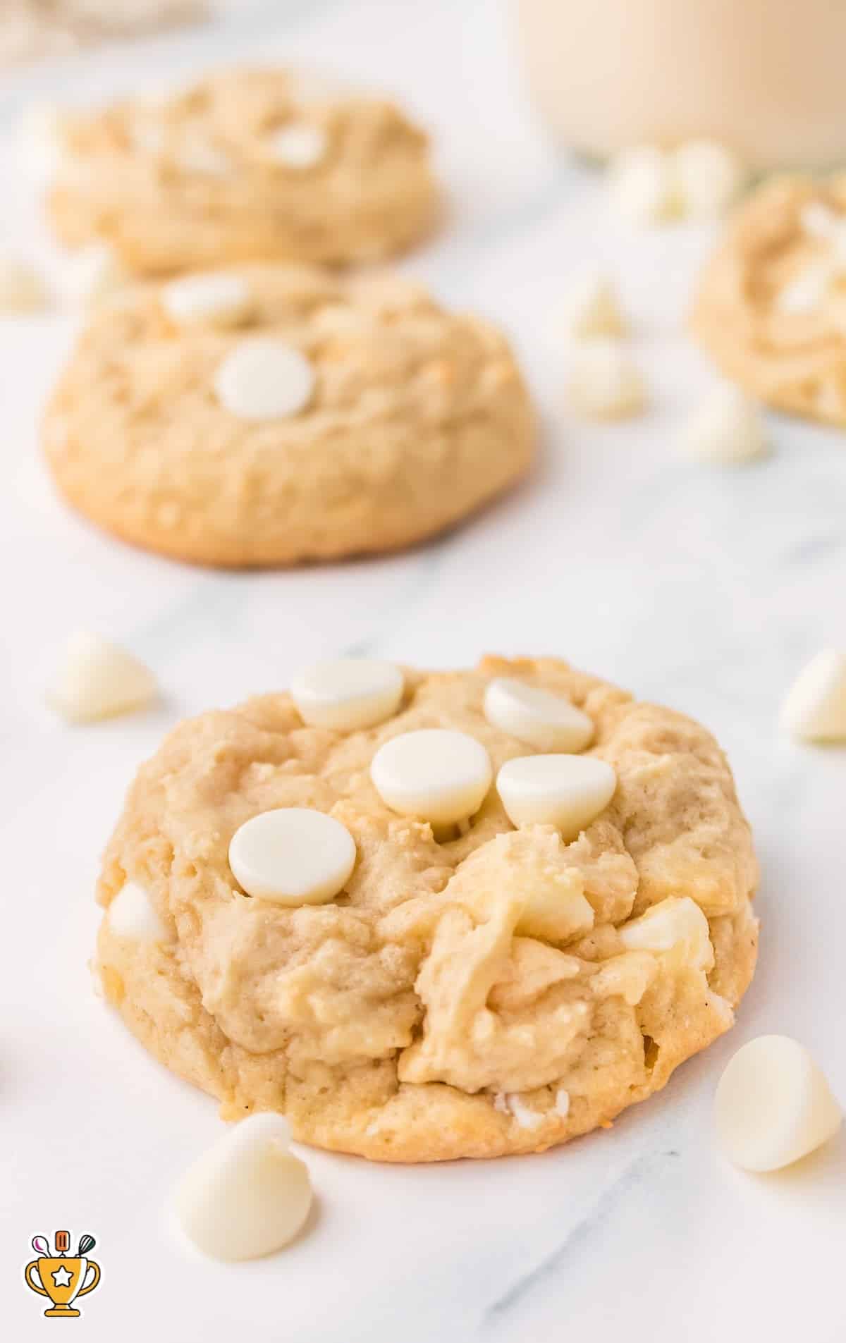 overhead shot of White Chocolate Chip Cookies on a baking sheet with a bowl of white chocolate chips