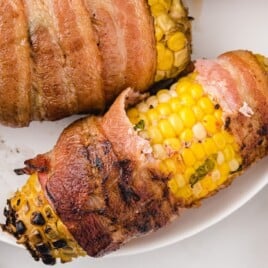 Piece of bacon wrapped corn on the cob with a bit.